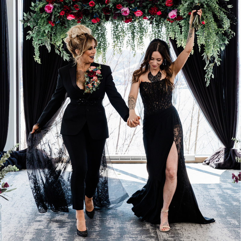 a just-married couple wearing black dresses walking down the aisle at EIX